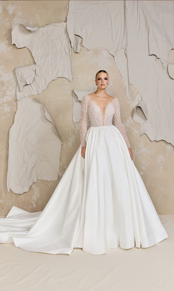 Luxuriöses Brautkleid mit glitzernden Details und einer weiten A-Linien-Silhouette, das durch die minimalistische Hintergrundgestaltung hervorgehoben wird.