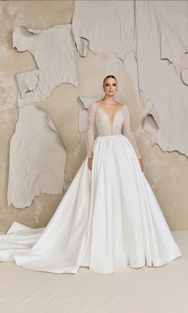 Luxuriöses Brautkleid mit glitzernden Details und einer weiten A-Linien-Silhouette, das durch die minimalistische Hintergrundgestaltung hervorgehoben wird.