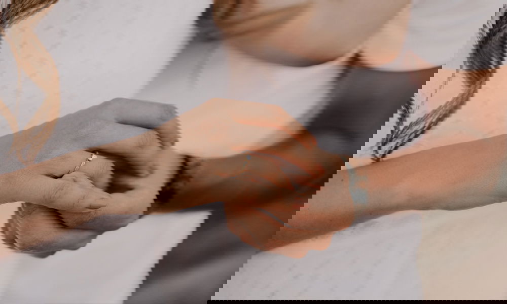 Romantischer Moment: Eine Frau zeigt stolz ihren Verlobungsring, während ihr Partner liebevoll ihre Hand hält.