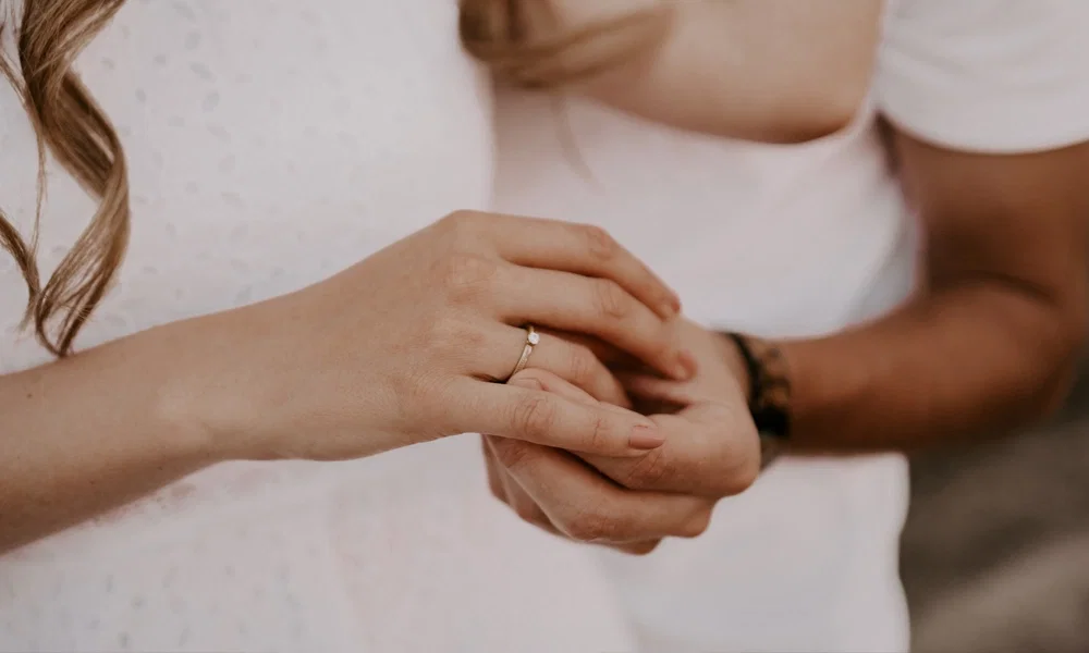 Romantischer Moment: Eine Frau zeigt stolz ihren Verlobungsring, während ihr Partner liebevoll ihre Hand hält.