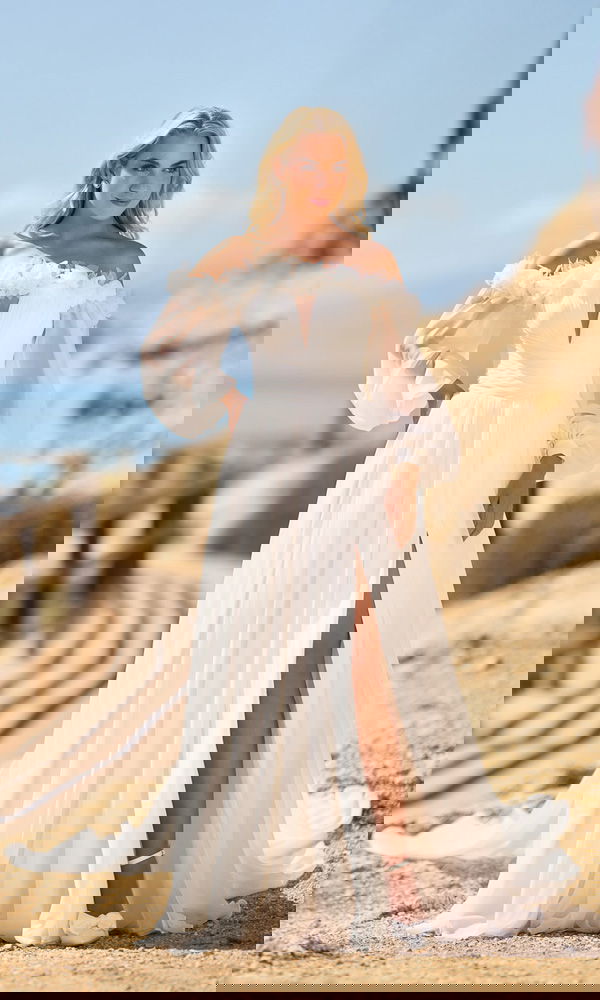 Fließendes Chiffonkleid mit Carmen-Ausschnitt, zarten Rüschen und hohem Schlitz – eine moderne Wahl für Brautpaare am Strand.