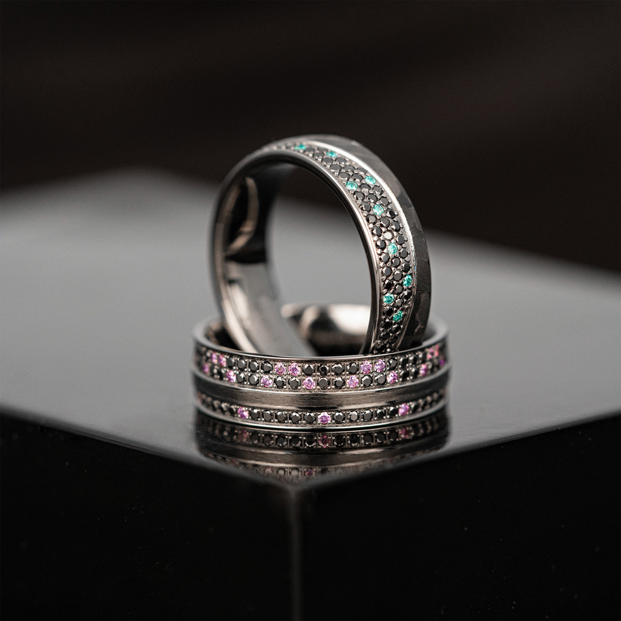 Dunkle Hochzeitsringe mit funkelnden Farbsteinen, die ein Statement setzen.