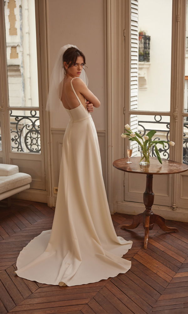 Zeitloses A-Linien-Brautkleid mit feinen Trägern und langer Schleppe, romantisch inszeniert in einer luxuriösen Altbauwohnung.