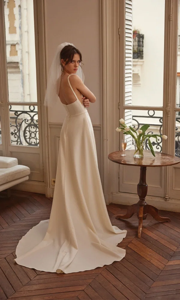 Zeitloses A-Linien-Brautkleid mit feinen Trägern und langer Schleppe, romantisch inszeniert in einer luxuriösen Altbauwohnung.