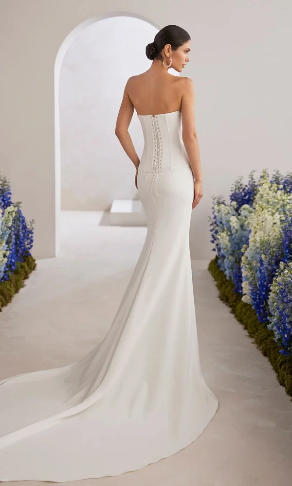 Braut in einem modernen trägerlosen Hochzeitskleid mit Schnürung am Rücken und fließendem Stoff, perfekt für eine stilvolle Zeremonie.
