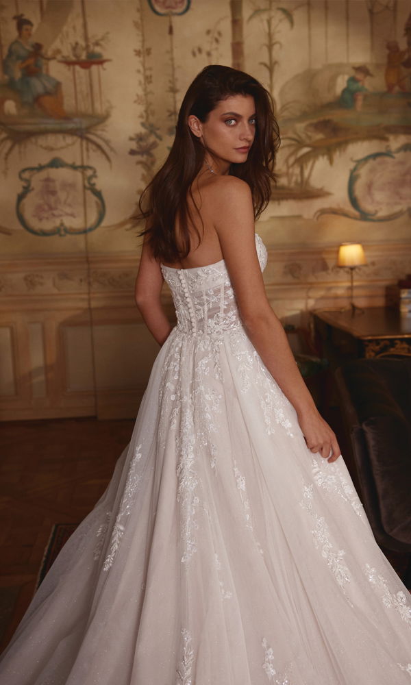 Romantisches Brautkleid mit aufwendiger Stickerei, das die Braut in einer historischen Umgebung mit eleganter Atmosphäre zum Strahlen bringt.