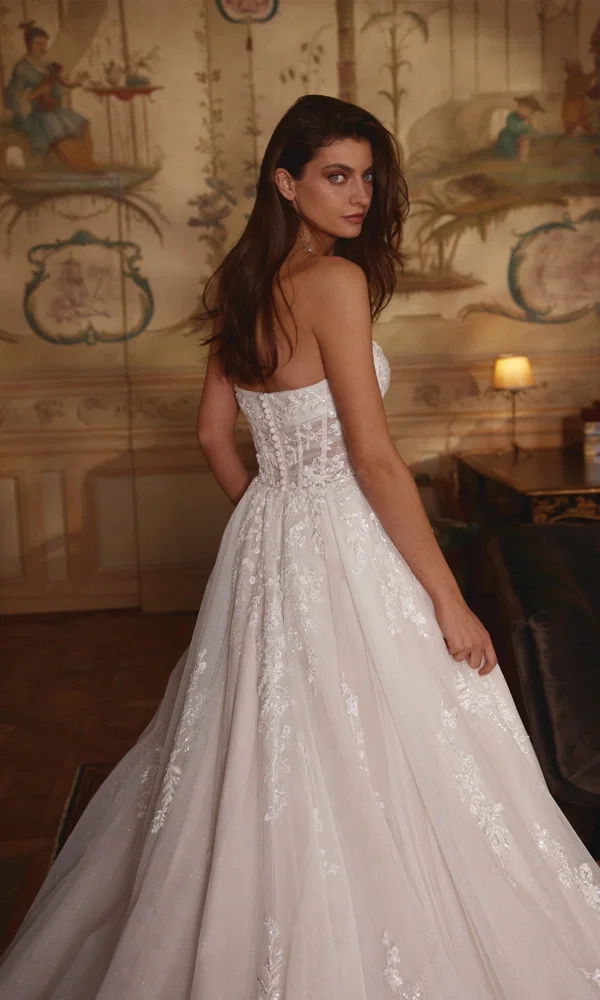 Romantisches Brautkleid mit aufwendiger Stickerei, das die Braut in einer historischen Umgebung mit eleganter Atmosphäre zum Strahlen bringt.