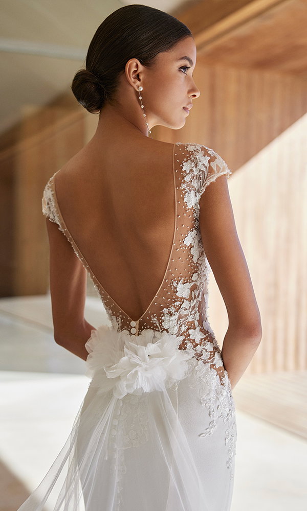 Feminin-verspieltes Brautkleid mit elegantem Blumendetail und transparentem Tüll auf dem Rücken.
