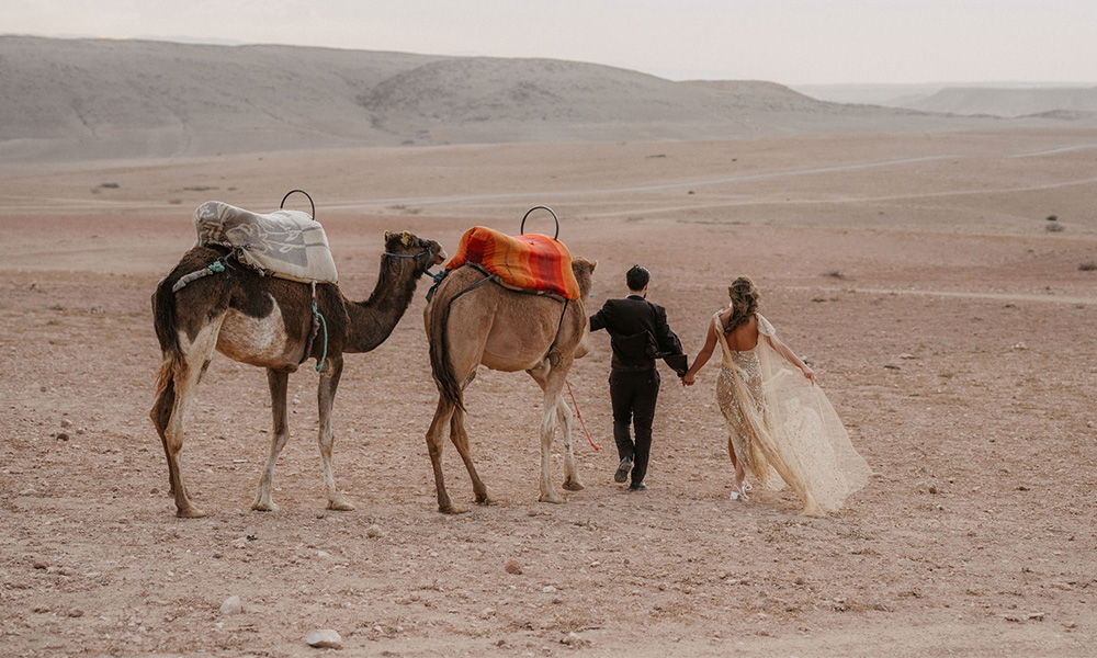 Hochzeitspaar in der Wüste auf dem Weg zu einem Abenteuer mit Kamelen.