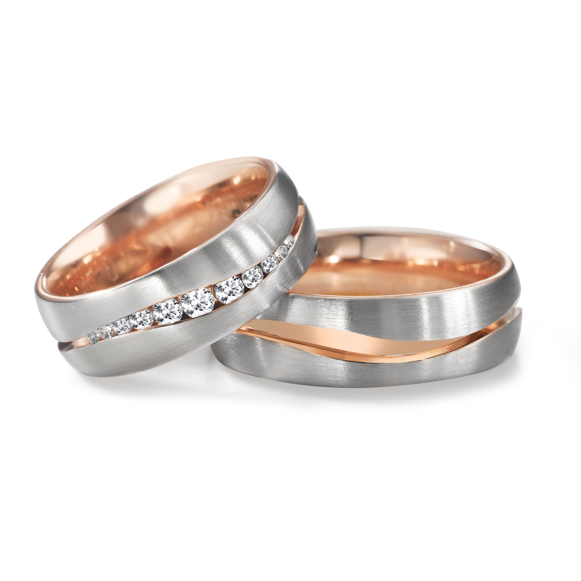 Zweifarbige Eheringe aus Weissgold und Roségold mit eingerahmten Diamanten im Damenring.