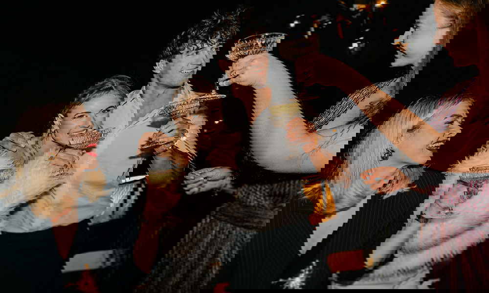 Modernes Hochzeitspaar feiert mit Freund:innen und Glitzerdeko.