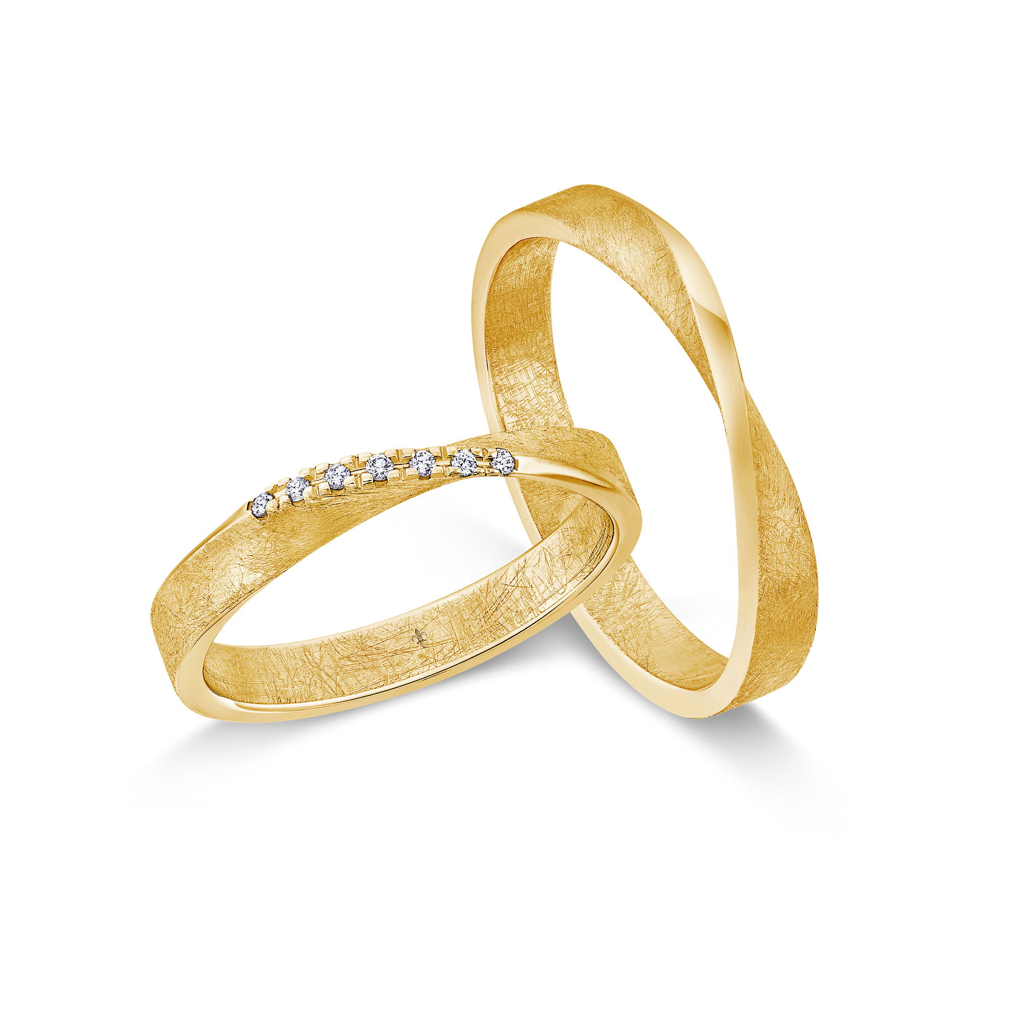 Handwerklich anmutende Gelbgoldringe mit natürlicher Oberfläche und funkelnden Steinen.