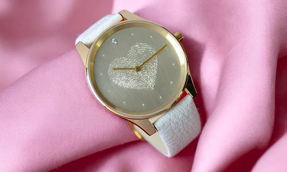 Eine Uhr von Vater& Sohn mit weißem Armband und Fingerabdruck in herzform im Ziffernblatt