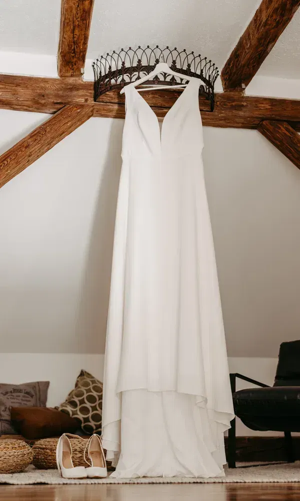 Minimalistisches Hochzeitskleid auf einem Kleiderbügel mit weißen Brautschuhen davor – bereit für den großen Tag.