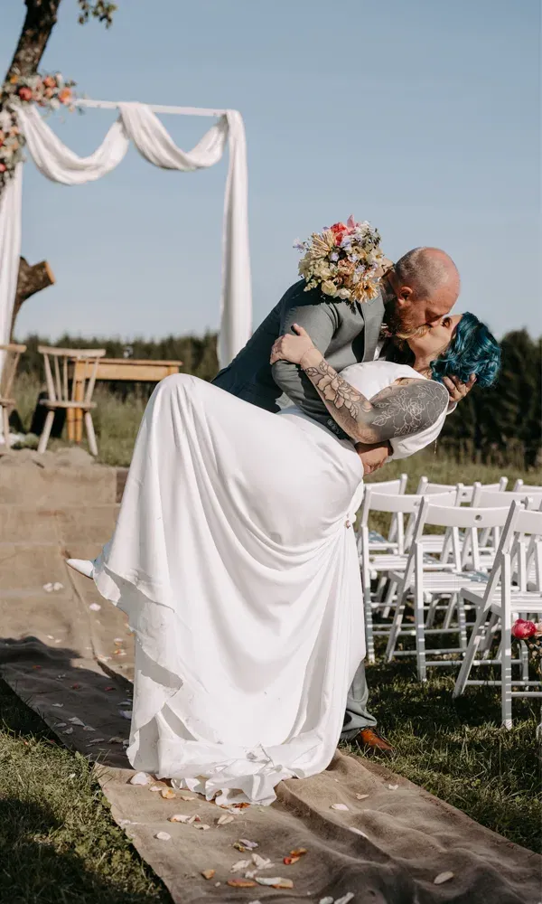 Florian hält Rebeka in den Armen, während sie sich küssend zurücklehnen – ein emotionaler Moment nach der Zeremonie im Freien.