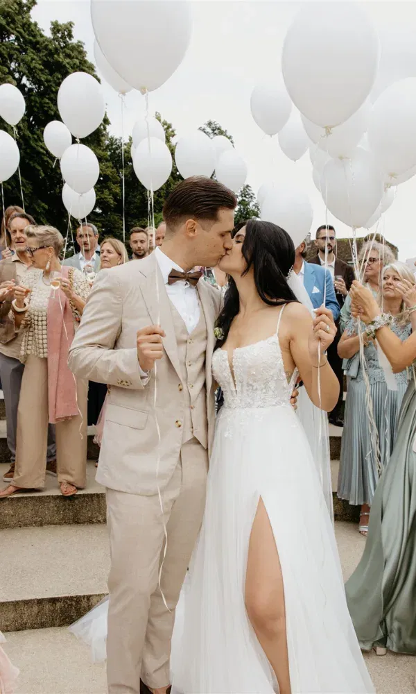 Ein Kuss unter weissen Ballons: ein Moment wie aus einem Traum.