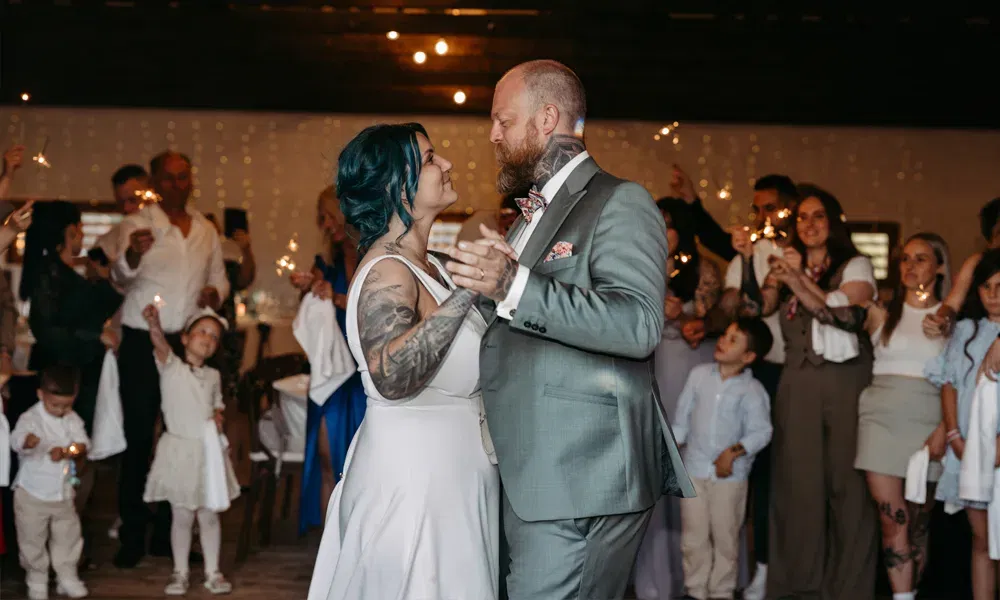 Inniger Tanzmoment beim Wedding-Weekend: Das Brautpaar tanzt eng umschlungen, während Gäste mit Wunderkerzen den Raum erhellen.