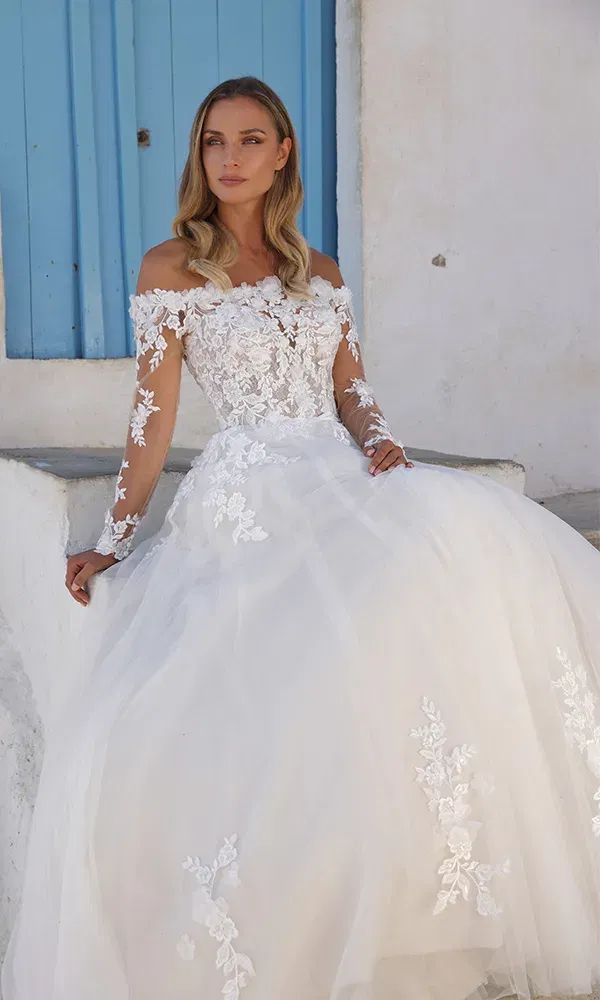 Romantisches Off-Shoulder-Brautkleid mit transparenter Spitze und floralen 3D-Applikationen, kombiniert mit einem weit ausgestellten Tüllrock.