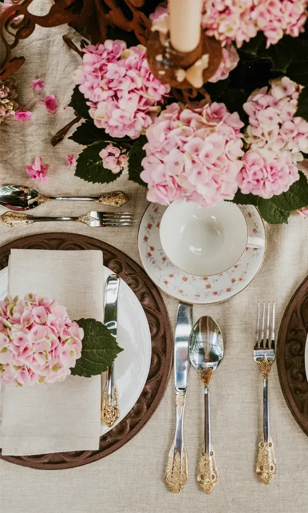 Feine Hochzeitstafel mit rosafarbenen Hortensien in Blumentöpfen und edlem Vintage-Besteck.