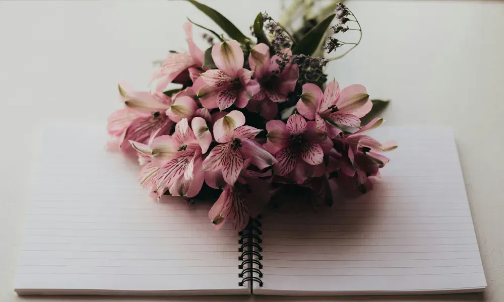 Blumenstrauß auf einem leeren Spiralbuch, bereit für persönliche Einträge, Erinnerungen oder Planungen zur Hochzeit.
