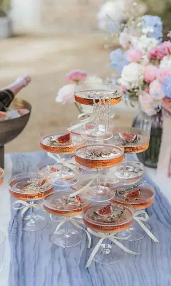 Roséfarbener Champagner in gestapelten Gläsern, garniert mit frischen Feigen und Schleifen, stilvoll für eine Feier angerichtet.