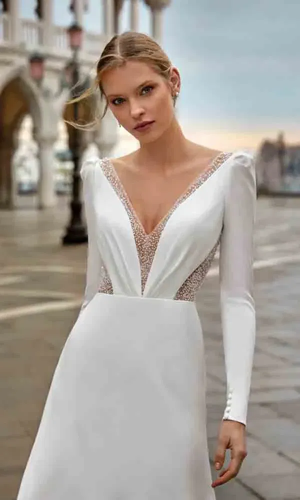 Braut in elegantem, langärmligem Kleid mit transparenten Spitzenelementen in venezianischer Kulisse.
