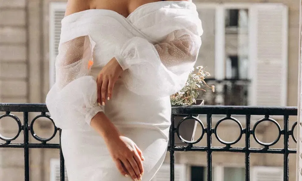 Schulterfreies Brautkleid mit zarten Puffärmeln aus Tüll – stilvolle Szene auf einem Balkon mit französischem Flair