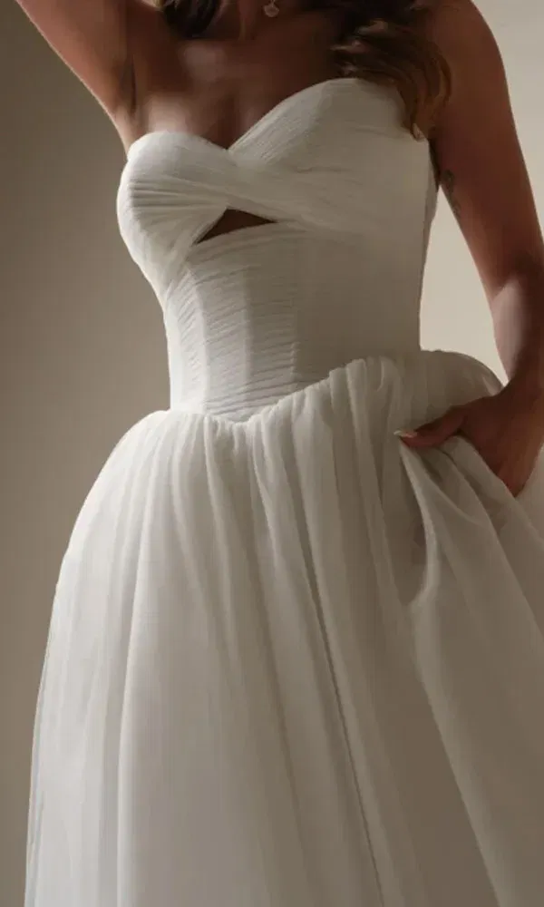 Brautkleid mit zartem Drapé-Mieder und kleiner Aussparung vorne, kombiniert mit einem voluminösen Rock aus Softtüll.