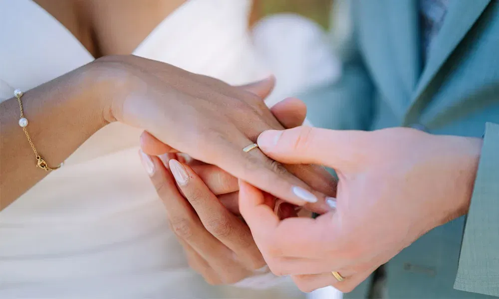 Nahaufnahme des Ringtauschs bei der Hochzeit – Bräutigam steckt der Braut den Ehering an