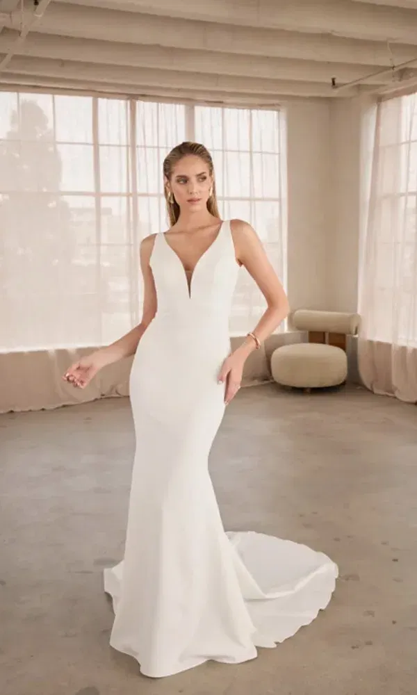 Zeitloses Hochzeitskleid in Ivory mit tailliertem Schnitt, breiten Trägern und dramatischer Schleppe in urbaner Studio-Atmosphäre.