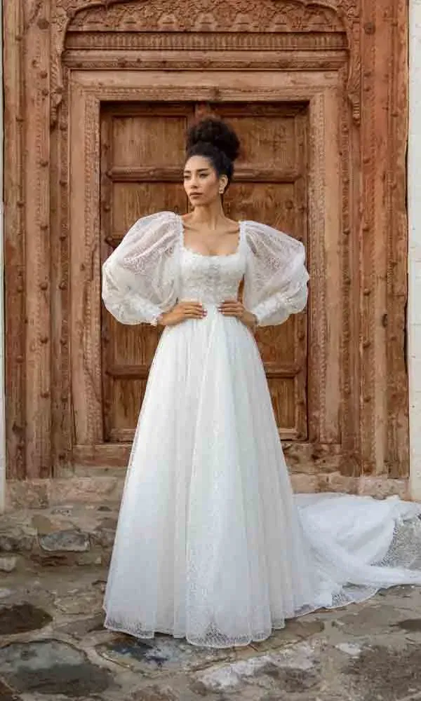 Vintage-inspirierter Hochzeitslook mit transparenten Puffärmeln und historischem Hintergrund.