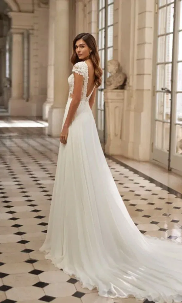 Rückenansicht einer Braut in einem klassischen A-Linien-Kleid mit feinen Spitzendetails und langem Schleppenteil auf schwarz-weißem Boden.