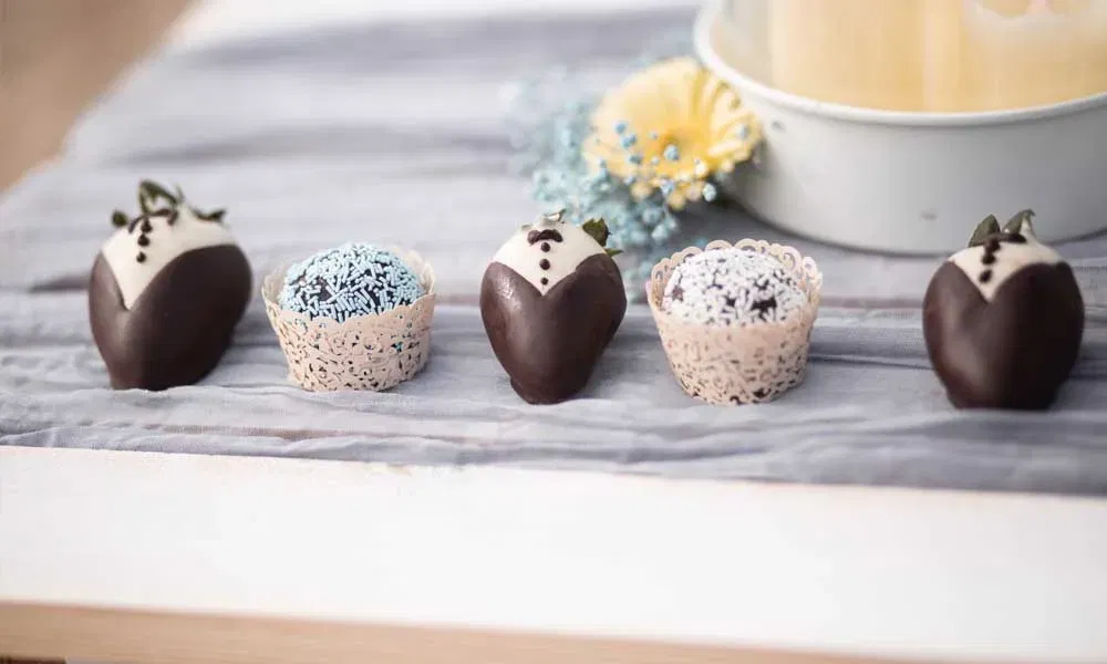Stilvolle Candybar-Details mit in Schokolade getauchten Erdbeeren im Tuxedo-Design und dekorierten Trüffeln – perfekt für eine festliche Feier.