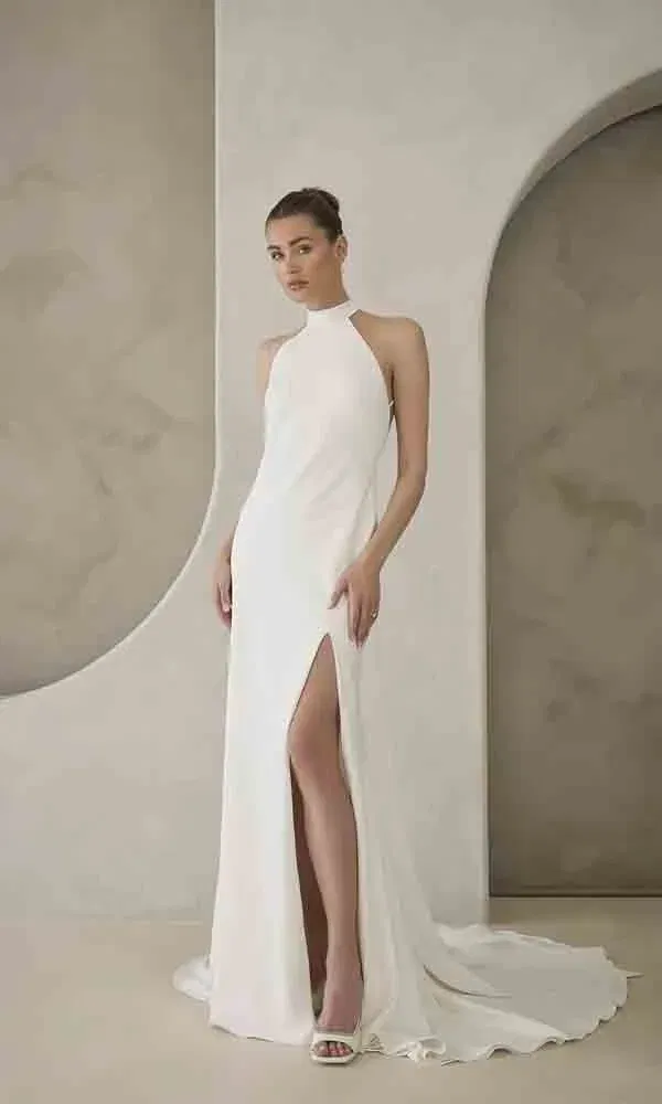 Minimalistisches Kleid mit sportlichem Halterneck und langer Schleppe – ideal für eine stilbewusste Braut mit modernem Geschmack.