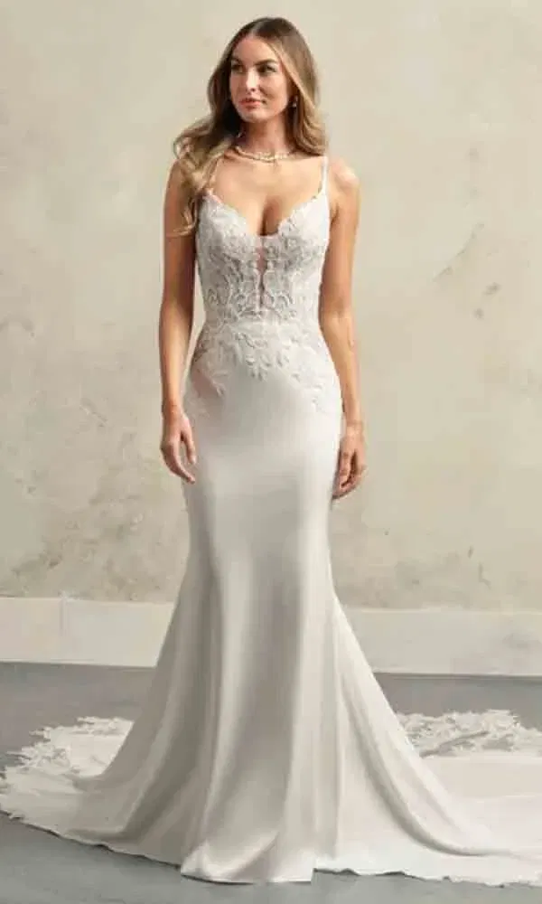 Schlanke Braut in einem elfenbeinfarbenen Hochzeitskleid mit langer Schleppe und feiner Spitzenverzierung.