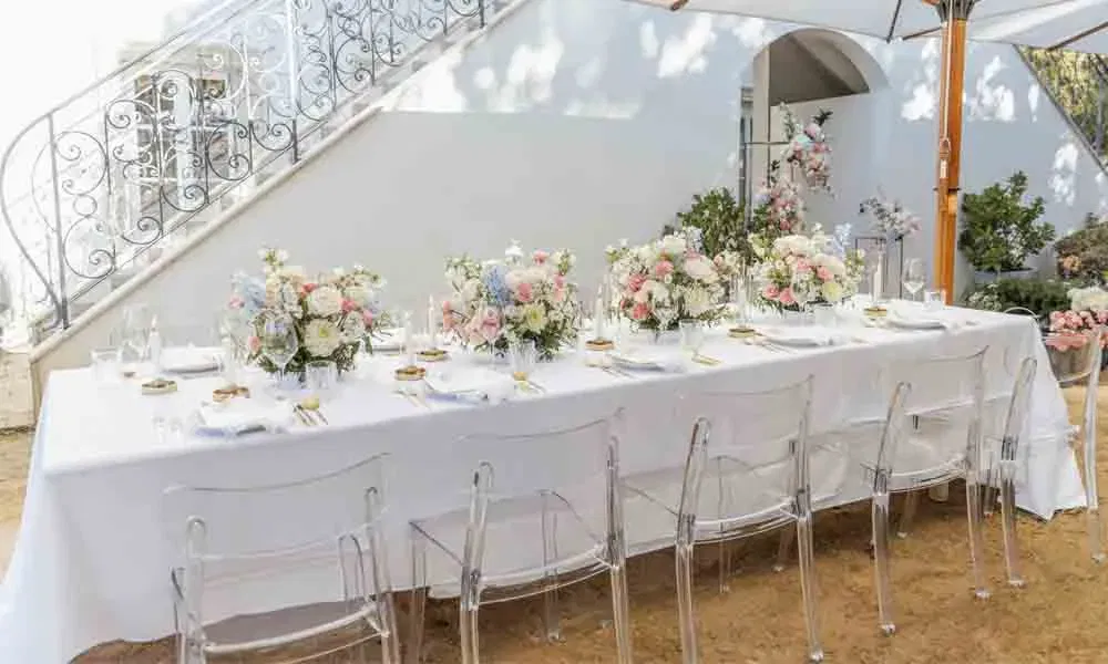 Festlich dekorierter Outdoor-Tisch für eine Hochzeitsfeier, mit hellen Blütenarrangements, stilvollem Geschirr und modernem Flair.