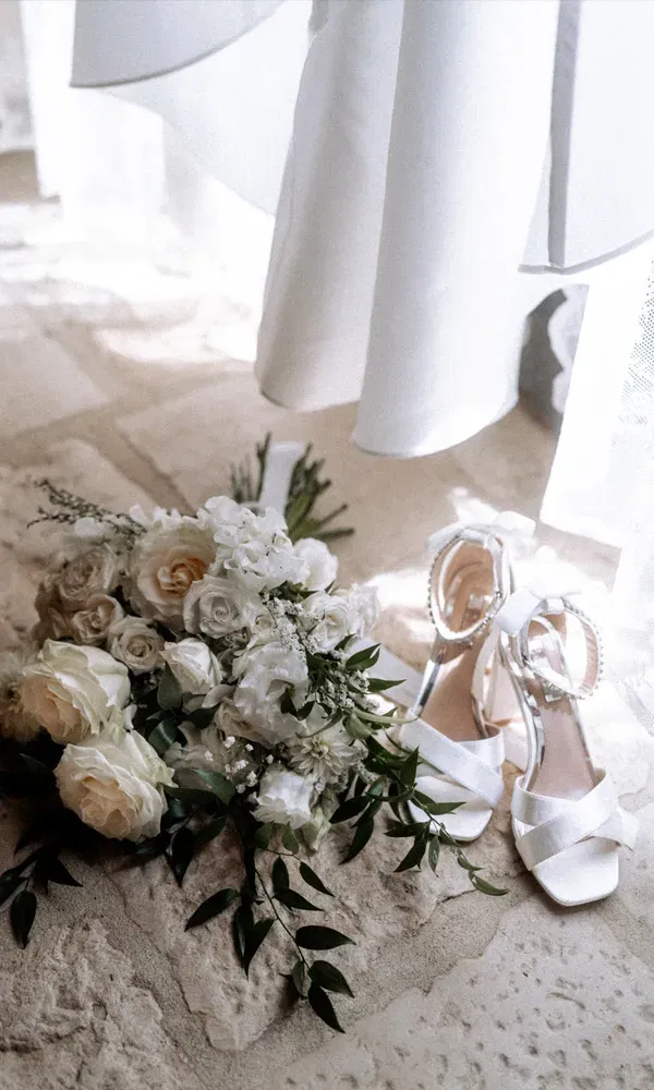 Romantische Nahaufnahme: floraler Brautstrauß und elegante Heels unter dem Kleid – bereit für den großen Auftritt.