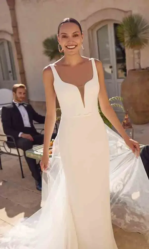 Elegante Braut mit tiefem V-Ausschnitt und feiner Stickerei auf dem Schleier in mediterranem Ambiente.