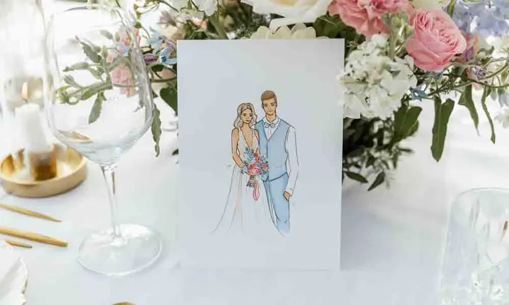 Künstlerisch gestaltete Karte mit Brautpaar-Zeichnung auf weißem Tisch, umrahmt von stilvoller Floristik und feinem Geschirr.