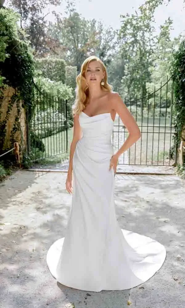 Zeitlos schönes Kleid im Outdoor-Setting – die Braut trägt eine trägerlose Robe mit schwungvoller Silhouette.