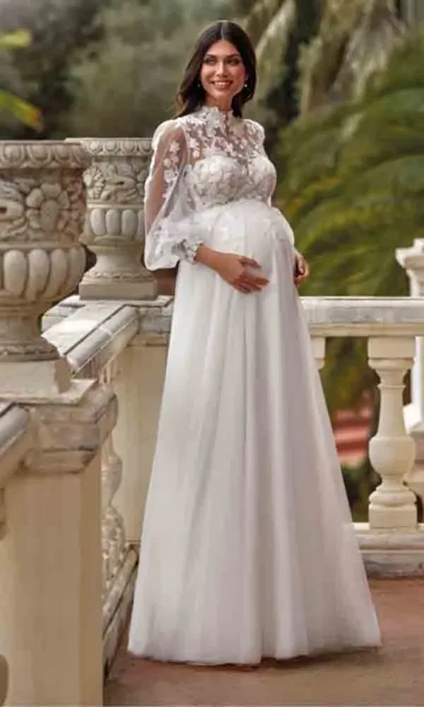 Umstandskleid mit langen Ärmeln aus Tüll und Spitze, inszeniert auf einem Balkon mit mediterranem Flair.