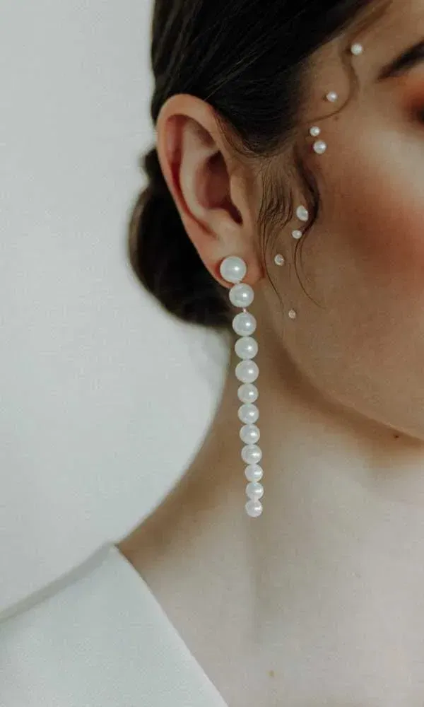 Modernes Braut-Styling mit langem Perlenohrring und perlenverzierten Gesichtspartien