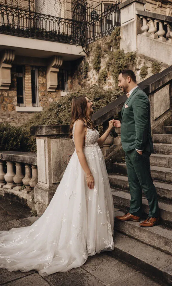 Romantische Szene eines Paares auf einer historischen Treppe – Braut sieht ihren Mann mit einem Lächeln an.