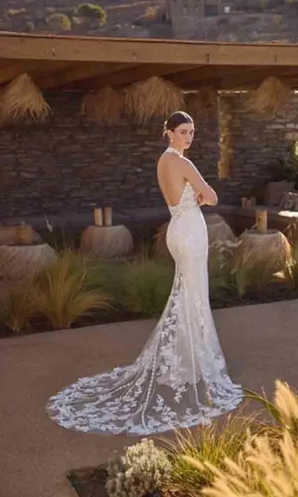 Braut in einem Spitzenkleid mit halter neck und zarter Tüllschleppe – perfekt für eine entspannte Hochzeit im Freien.