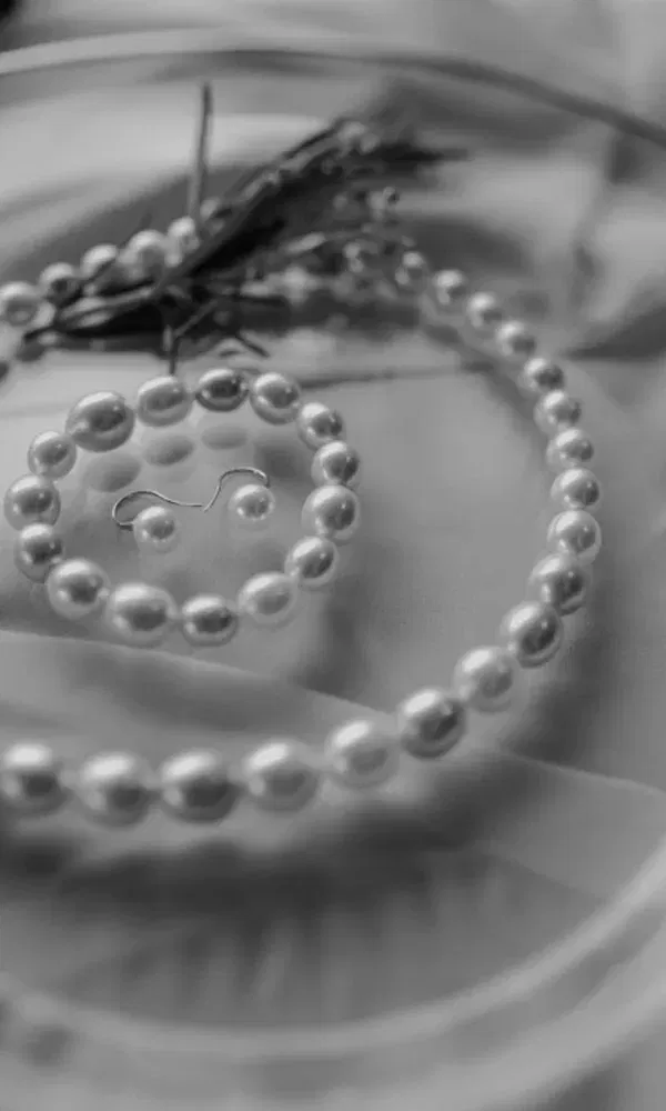 Nahaufnahme eines runden Perlensets bestehend aus Kette und Armband, kunstvoll arrangiert auf Satin.