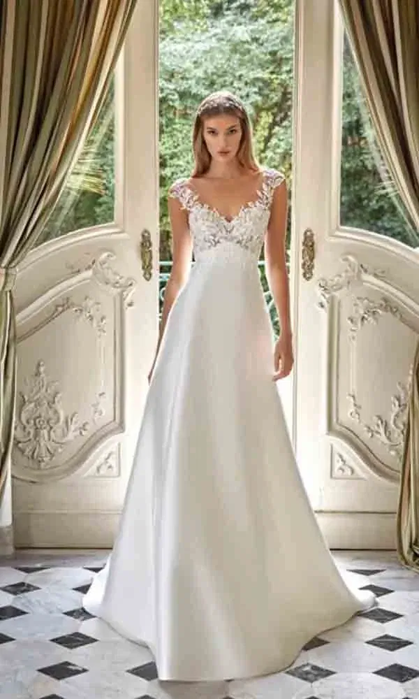 Eleganter Brautlook in einem ausladenden Kleid mit floraler Spitze und nostalgischem Ambiente im Hintergrund.