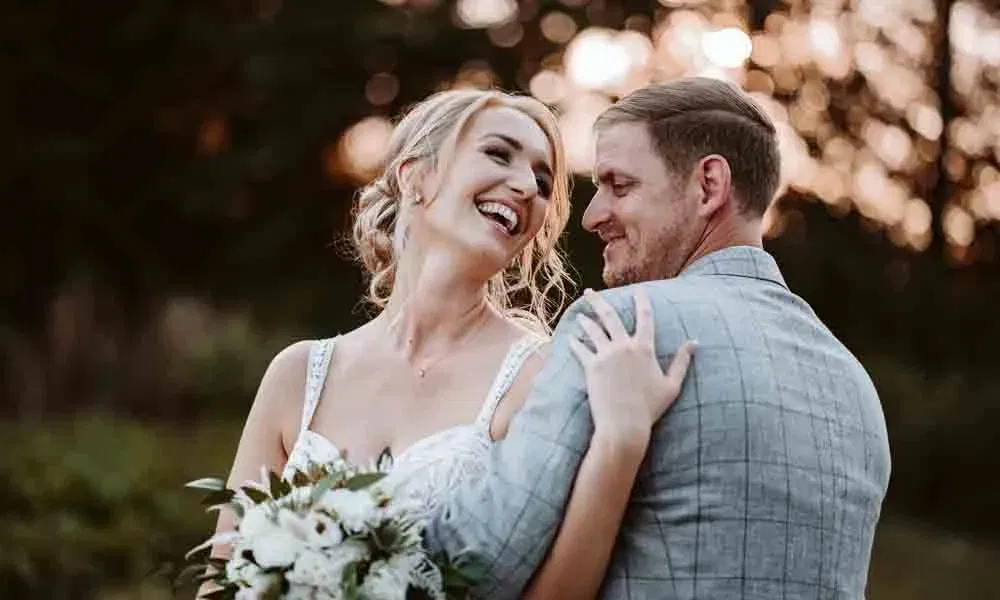 Romantisches Porträt eines Brautpaares bei Sonnenuntergang, mit liebevollem Blick und warmer Lichtstimmung im Hintergrund.