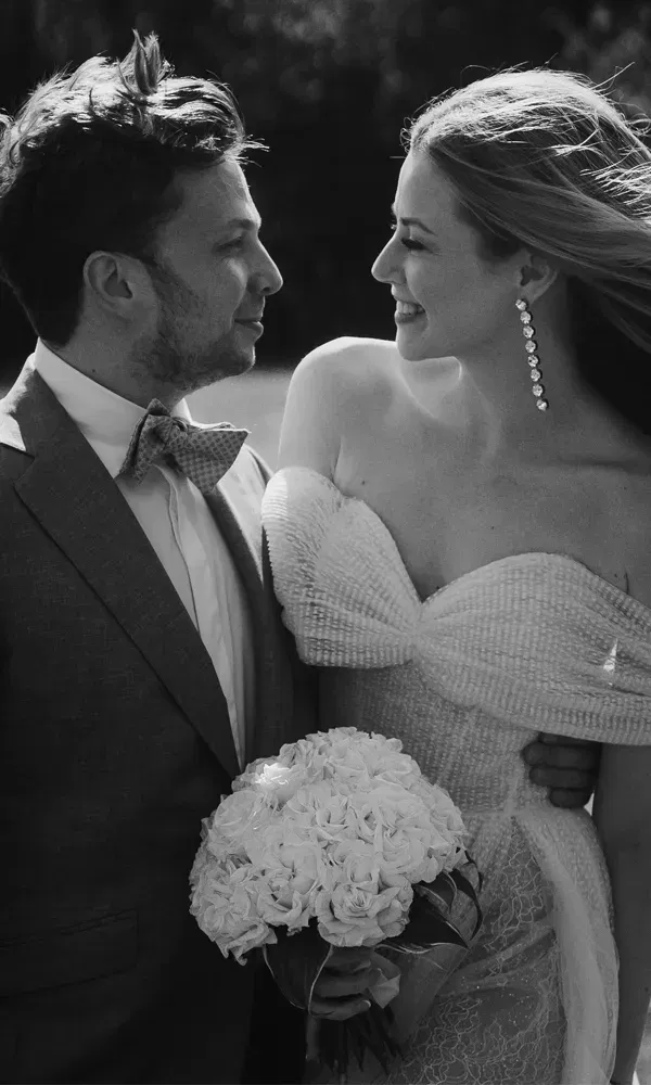 Romantisches Hochzeitsfoto in Schwarz-Weiß mit engem Blickkontakt zwischen dem frisch verheirateten Paar und einem Rosenstrauß im Vordergrund.