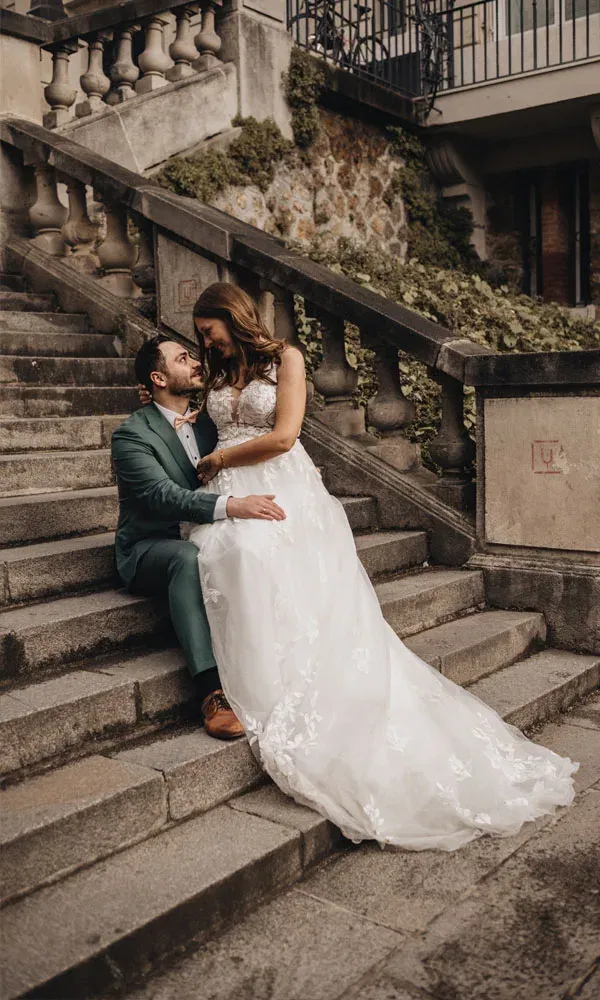 Sebastian und Katharina in einem emotionalen Augenblick – vertrauter Blick auf den Stufen eines historischen Gebäudes.