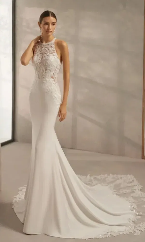 Hochgeschlossenes Brautkleid mit floralen Stickereien und Schleppe, perfekt inszeniert in einem modernen Fotostudio.